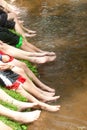 Group of kids sitting on bank with feet over water