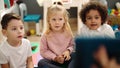 Group of kids sitting on floor having lesson with touchpad at kindergarten Royalty Free Stock Photo