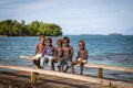 Group of kids sitting on wooden pier, Solomon Islands