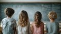 A group of kids stand in front of the chalkboard in a classroom setting. Royalty Free Stock Photo