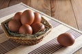 Group of large brown chicken eggs lies in a wicker basket and one lies next to the basket, on a wooden table Royalty Free Stock Photo
