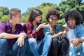 Group of latin and african american young adults watching clip on phone Royalty Free Stock Photo