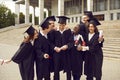 Group of laughing happy multiracial graduates hugging outdoors holding diploma. Royalty Free Stock Photo