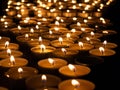 Tea candles in a row burning on black background Royalty Free Stock Photo