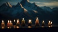a group of lit candles sitting on top of a wooden table in front of a snow covered mountain range in the distance, with a dark Royalty Free Stock Photo