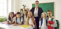 Group little children posing together with female primary school teacher after finishing lessons