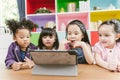 Group of little children watching film movie cartoon together on digital tablet. Kids playing with tablet with friends at home.