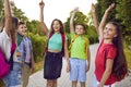 Group of little school friends raise their hands in air after stacking them while walking in park. Royalty Free Stock Photo