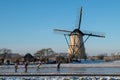 Group of locals on a frozen windmill canal pathway at sunrise moment Royalty Free Stock Photo