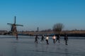 Group of locals on a frozen windmill canal pathway at sunrise moment