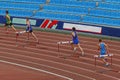 group male athletes running 400 meters hurdles in summer athletics