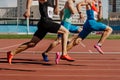 group male athletes sprinting on red track stadium