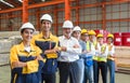 Group of male and female factory labor stand smiling together with arms crossed in industry factory. Everyone wearing safety Royalty Free Stock Photo