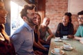 Group Of Male And Female Friends Meeting For Coffee Sitting At Table Together