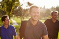 Group Of Male Golfers Walking Along Fairway Carrying Bags Royalty Free Stock Photo