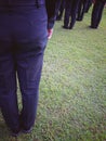 A group of male soldiers wear uniforms, standing in line at the lawn.