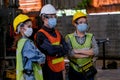 Group of man and woman workers with hygiene mask stand in confident action in the factory area