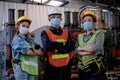 Group of man and woman workers with hygiene mask stand in confident action in the factory area