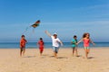 Group of many kids run with kite on a sand beach