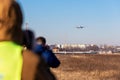 Group of many people watching planes landing and take off airport runway field planespotting conference warm morning Royalty Free Stock Photo