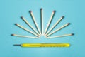 A group of matches ready to light forming a sun on top of a hot mercury thermometer on a colorful blue background. Royalty Free Stock Photo