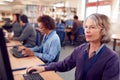 Group Of Mature Adult Students In Class Working At Computers In College Library