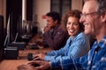 Group Of Mature Adult Students In Class Working At Computers In College Library