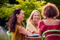 Group Of Mature Female Friends Talking Around Table At Summer Dinner Party In Garden At Home