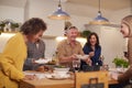 Group Of Mature Friends Meeting At Home Serving Food At Dinner Party And Drinking Wine Together Royalty Free Stock Photo