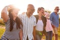 Group Of Mature Friends On Vacation Walking Along Path Through Campsite At Sunset