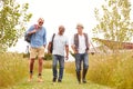 Group Of Mature Male Friends Walking Along Path Through Yurt Campsite