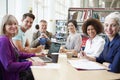 Group Of Mature Students Collaborating On Project In Library