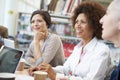 Group Of Mature Students Collaborating On Project In Library