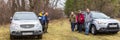 A group of mature tourists is standing near cars