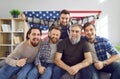 Group of men with American flag sitting on couch and watching soccer match on TV Royalty Free Stock Photo