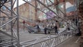 Group of men fixate grey opaque tarpaulin dome onto metallic stage structure