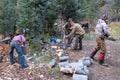 Group of men hunters chop and split logs and wood for campfires, while on an elk hunting