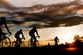 Group of men ride bicycles at sunset with sunbeam over