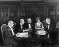 Group of men sitting with a young woman in a boardroom