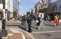 A group of men and women are crossing the street while an African American female police officer is controlling the traffic.