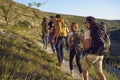 Group of men and women walk in a row along the trail during a walking tour of the mountains. Royalty Free Stock Photo