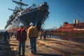 A group of men working on a dock next to a large ship in ship repair factory. Back side view. Ship building Royalty Free Stock Photo