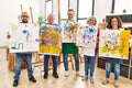 Group of middle age draw students smiling happy holding drawing canvas at art studio Royalty Free Stock Photo