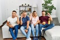 Group of middle age people sitting on the sofa at home smiling and confident gesturing with hand doing small size sign with Royalty Free Stock Photo