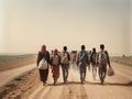 A group of migrants with children walk along a dusty road.