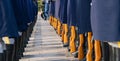 Group of military personnel in navy uniforms marching in formation past a row of military boots.