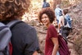 Group of millennial friends hiking uphill on a forest trail, waist up