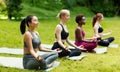 Group of millennial girls attending yoga meditation class at park, blank space