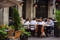 Group of millennials eating dinner outside at upscale restaurant