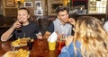 Group of millennials friends eating at fast food indoors in irish pub restaurant. Happy people partying and eating together. Young Royalty Free Stock Photo